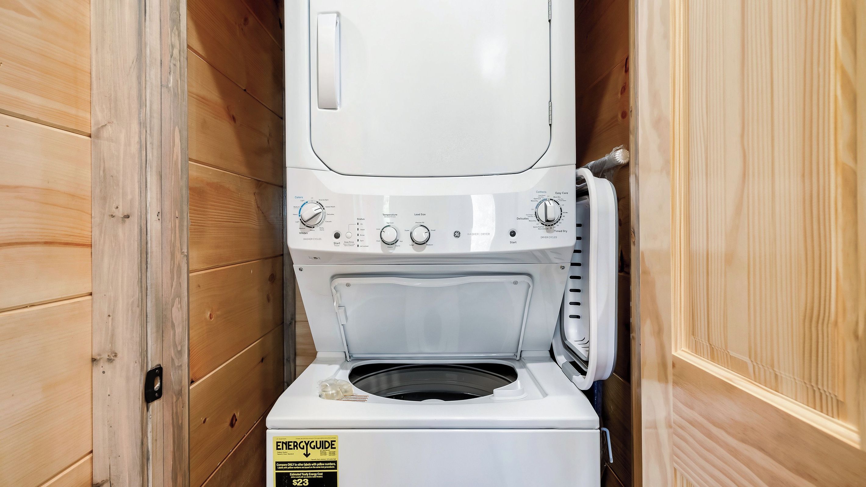 A compact washer and dryer unit installed in a wooden closet.