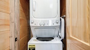 Un appareil combiné lave-linge et sèche-linge, de dimensions réduites, installé dans un placard en bois.