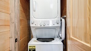Una lavadora y secadora compactas instaladas en un armario de madera.