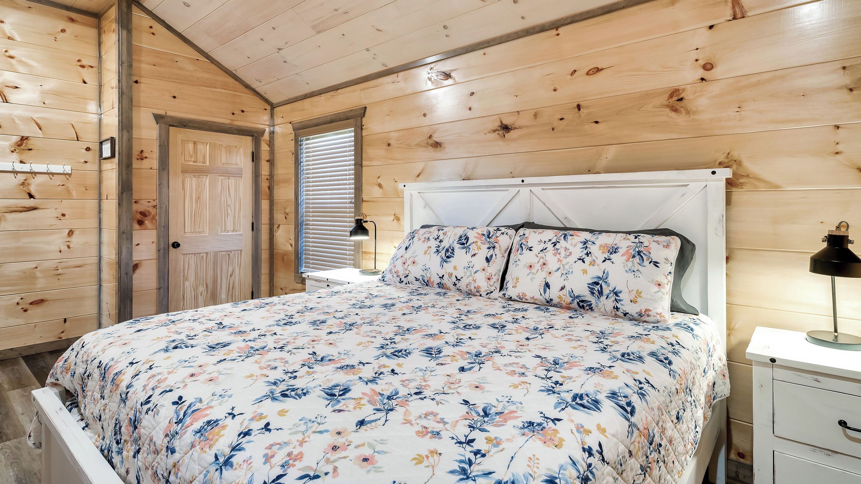 A wooden-paneled bedroom with a bed, a bedside table, and a nightstand.