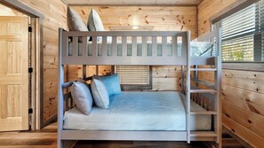 Una cama litera con una cama inferior, una ventana con persianas y una puerta con picaporte.