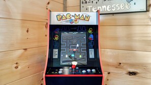 Una máquina arcade de Pac-Man con un indicador de puntaje, controles de juego y un letrero que dice 'Tennessee' al fondo.