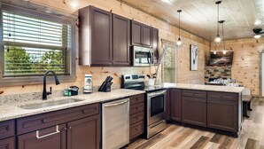 Une cuisine moderne avec des meubles en bois foncé, des appareils électroménagers en acier inoxydable et un plan de travail en granit.