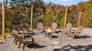 An outdoor seating area with Adirondack chairs and a fire pit.
