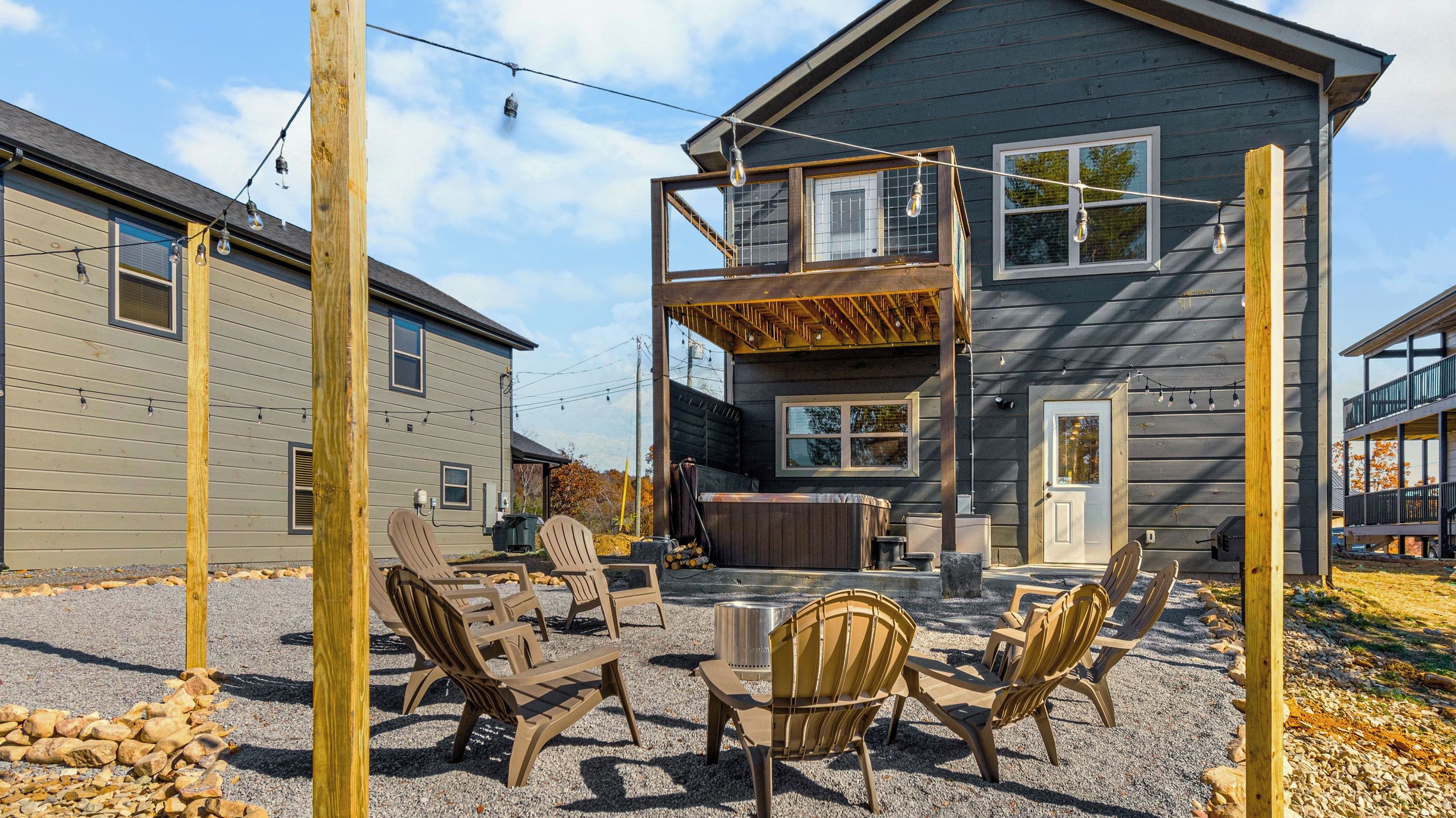 A two-story house with a deck, outdoor seating, and a hot tub.