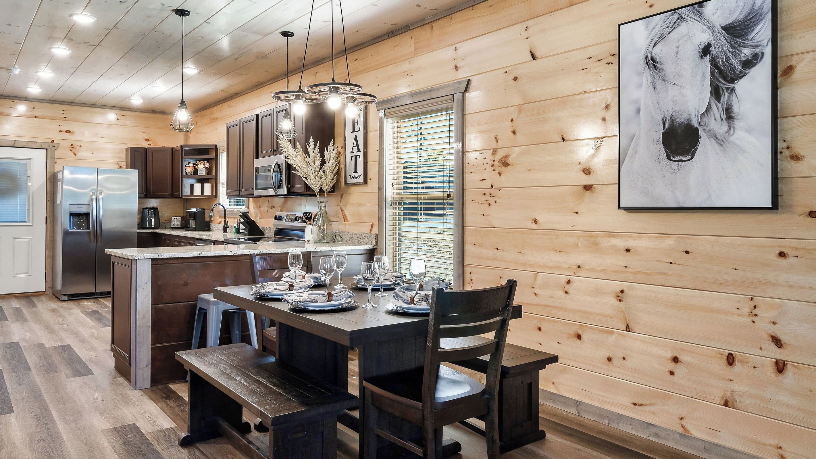 A wooden interior with a dining area, kitchen, and a mounted artwork.