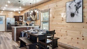 Un interior de madera con comedor, cocina y una obra de arte colgada.