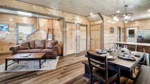 A wooden interior with a sofa, dining table, and chairs. - Cabin Bliss | Hot Tub, Games & Scenic Yard Escape (Sevierville)