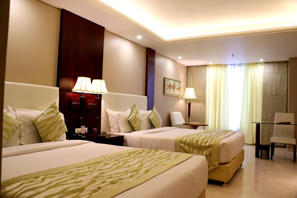 Habitación de hotel con dos camas, un escritorio y una silla.