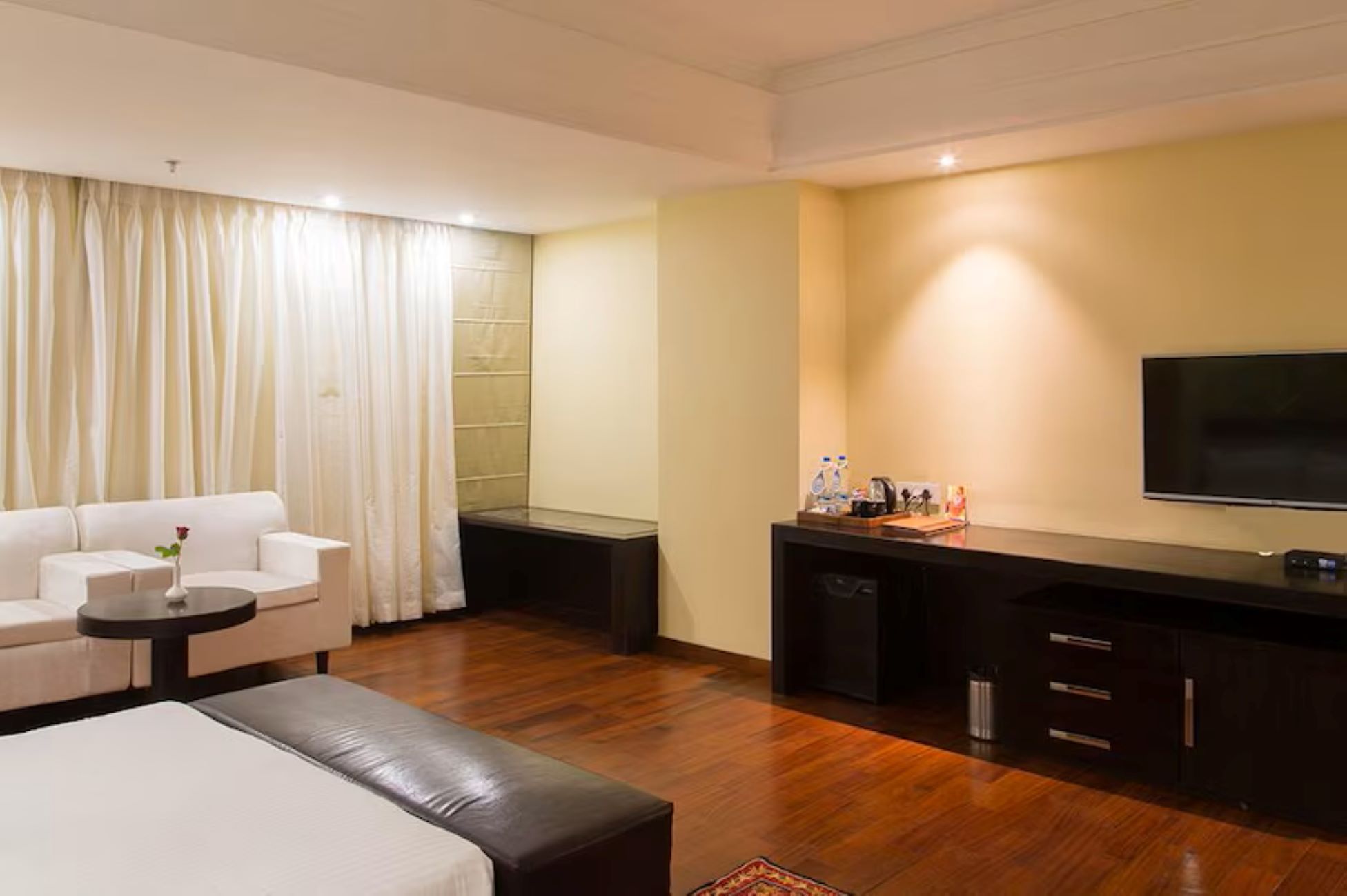 Een hotelkamer met een bank, een kleine tafel, een salontafel, een televisie en een minibars.