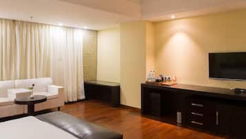 Een hotelkamer met een bank, een kleine tafel, een salontafel, een televisie en een minibars.