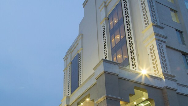 A multi-story hotel with a modern architectural design, featuring large windows and a well-lit facade. - Trinity Grand (Raigarh)