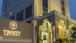 A modern hotel with a prominent entrance, large windows, and a well-lit facade. - Trinity Grand (Raigarh)