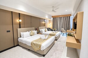 Una habitación de hotel moderna con una cama grande, un escritorio, una silla y un ventilador de techo.