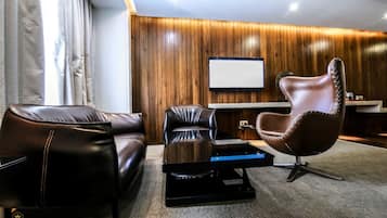 A modern living room with leather sofas, a unique chair, a flat-screen TV, and a wooden wall.