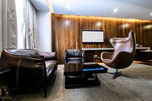 A modern living room with leather sofas, a unique chair, a flat-screen TV, and a wooden wall.
