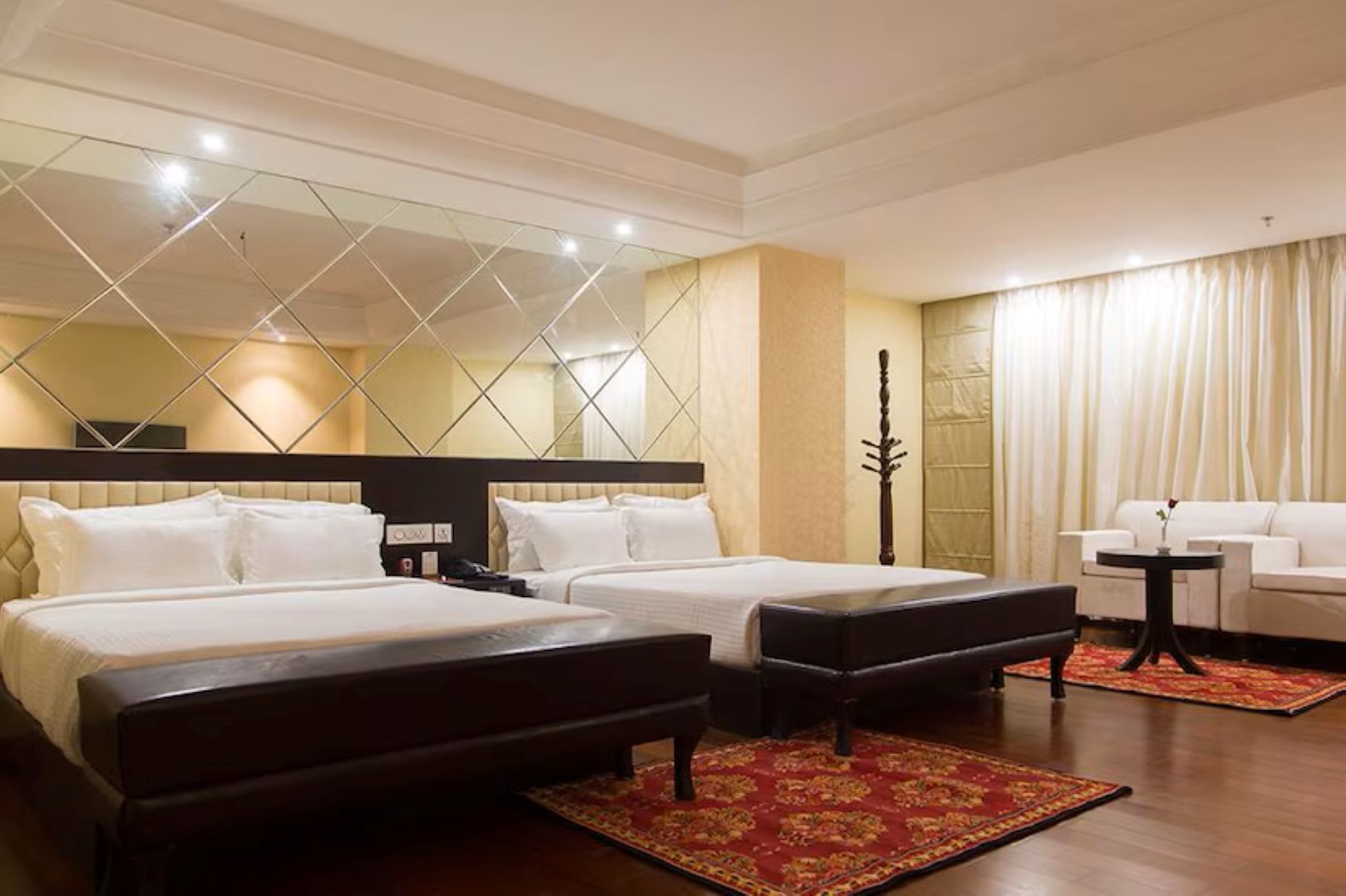 Habitación de hotel con dos camas, un área de descanso con una silla y un adorno en la pared.
