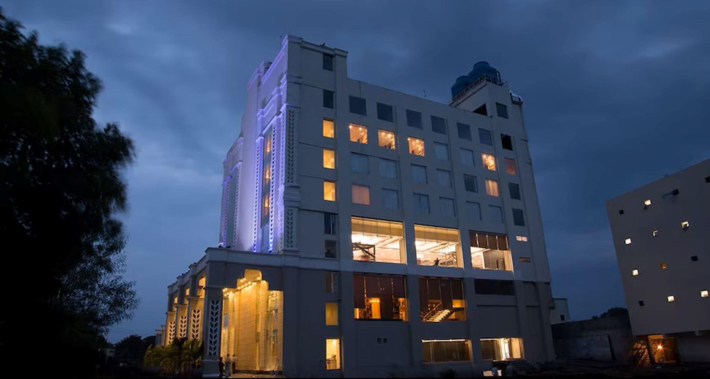 Un hôtel à plusieurs étages, avec des fenêtres illuminées et une structure verticale imposante sur le côté gauche.
