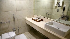 A bathroom with a toilet, bidet, and a large sink with a mirror above it. - Trinity Grand (Raigarh)