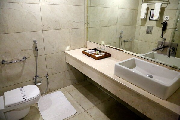Une salle de bain comprenant des toilettes, un bidet et un grand lavabo avec un miroir au-dessus.
