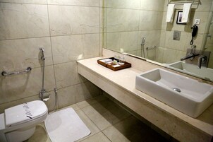 A bathroom with a toilet, bidet, and a large sink with a mirror above it.