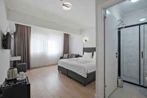 Une chambre d’hôtel moderne équipée d’un lit, d’un bureau avec une bouilloire, d’un espace douche et offrant une vue sur l’extérieur.