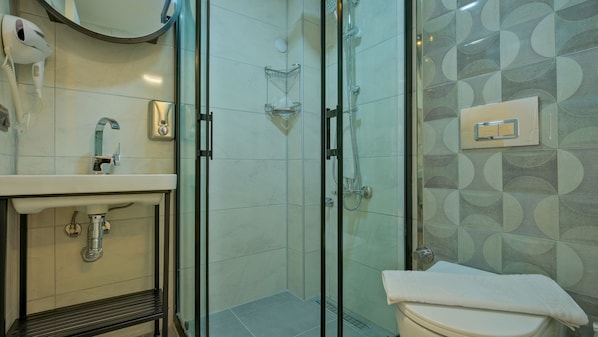 Un baño moderno con ducha de vidrio, lavamanos con espejo y retrete.