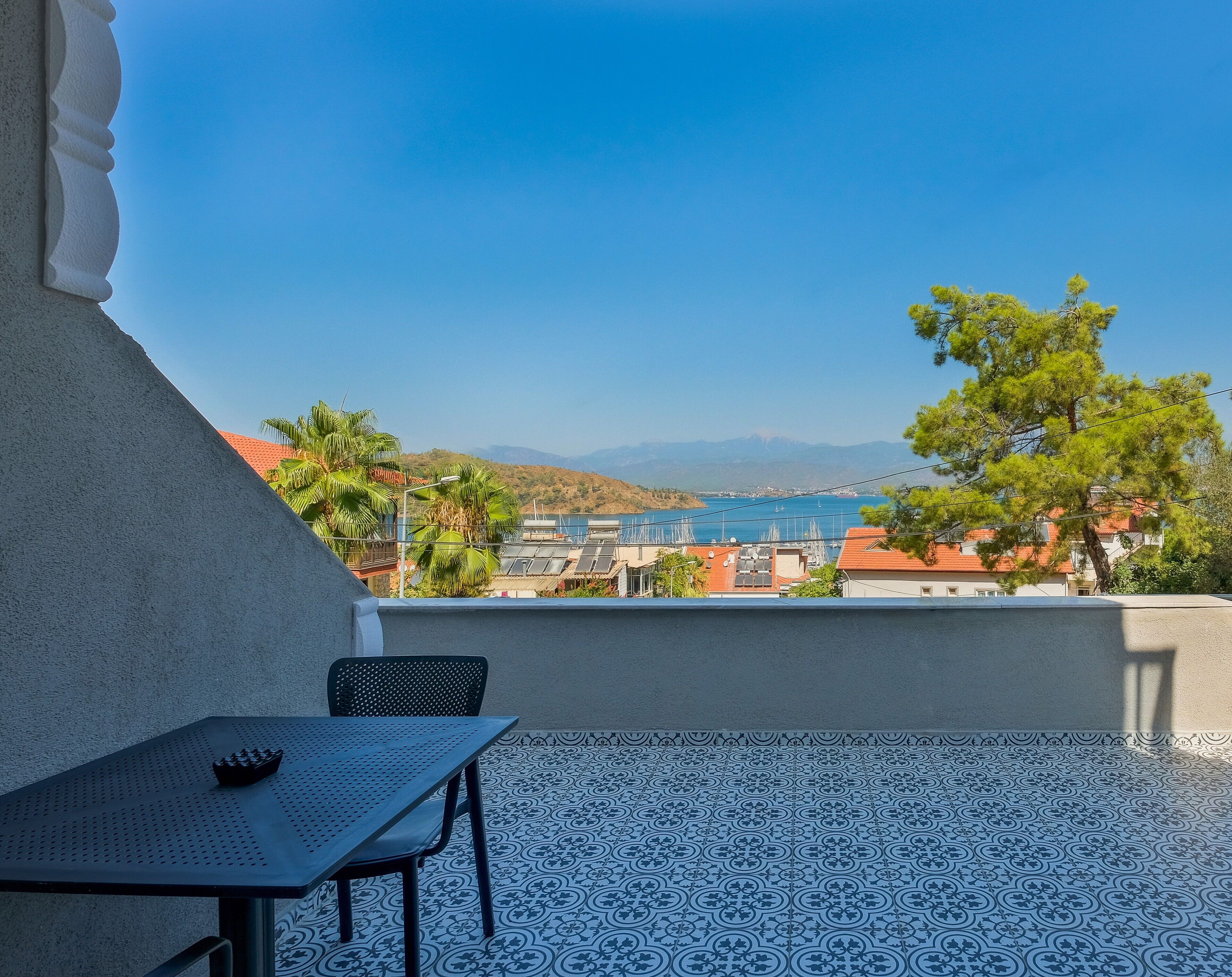 A balcony with a patterned floor, a table, and a chair.