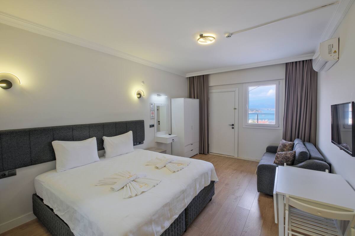 Una habitación de hotel con cama, escritorio, sofá, armario y vista al mar.