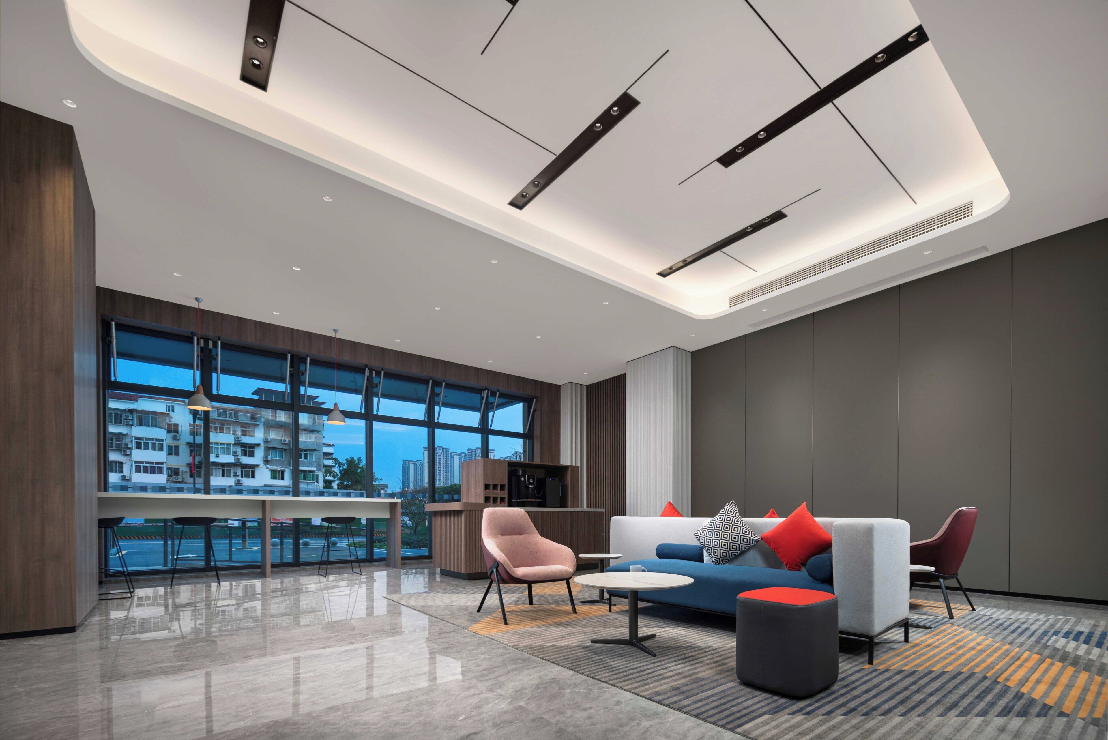 A modern hotel lobby with a large window, a sofa set, a coffee table, and a small table with a chair.