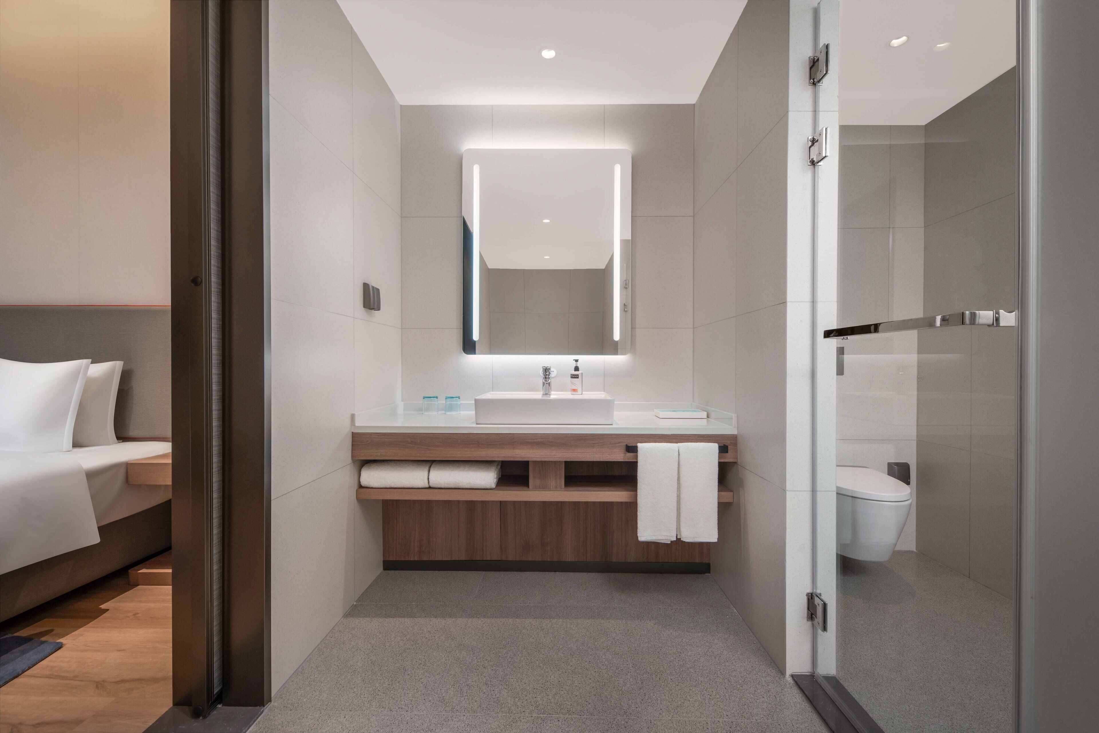 A modern bathroom with a large mirror, a sink, and a shower area.