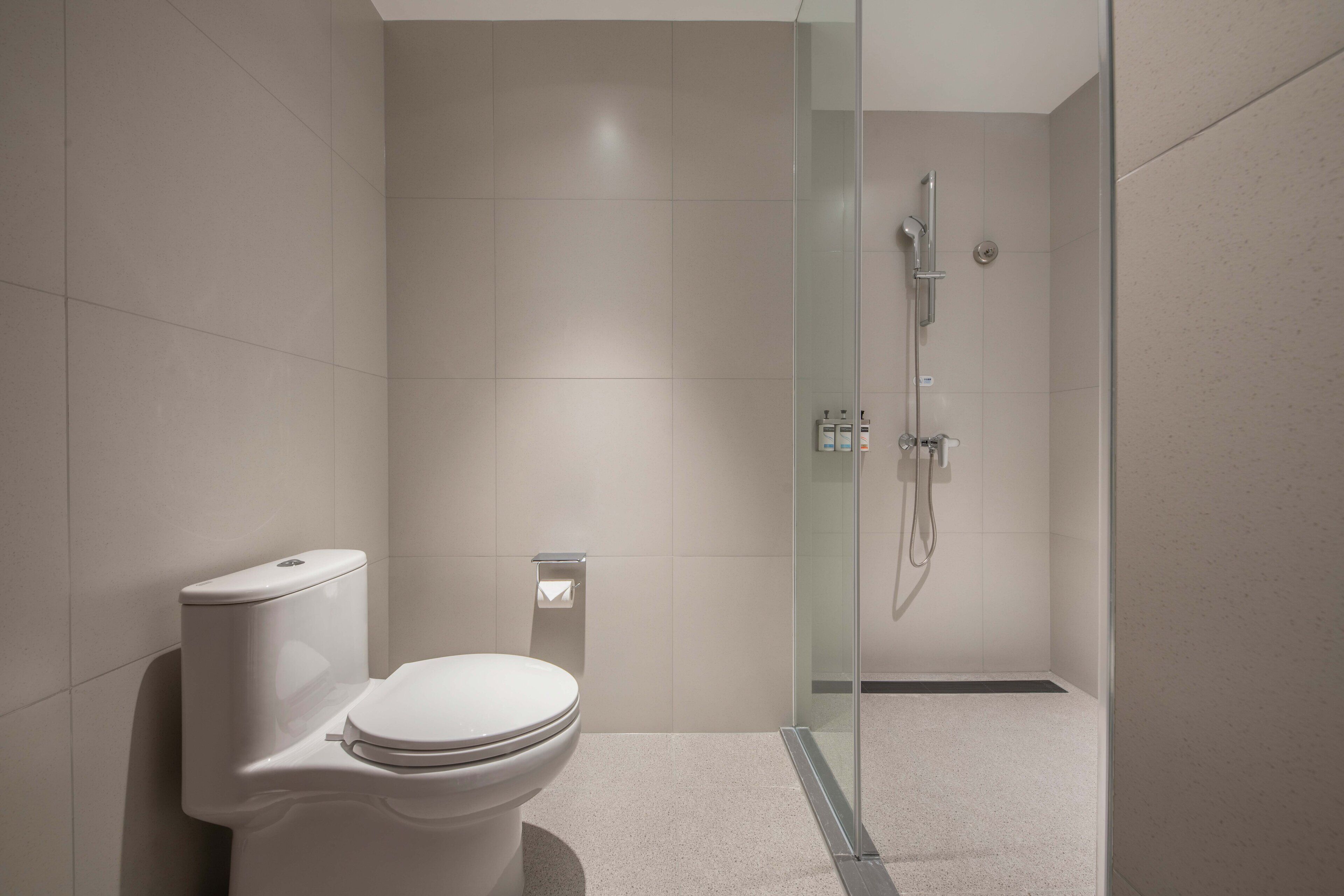 A modern bathroom with a toilet, a glass shower enclosure, and a tiled floor.