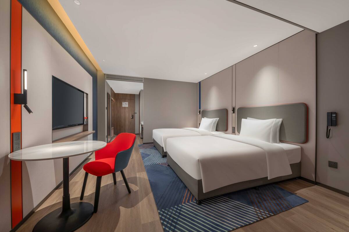 Ein modernes Hotelzimmer mit einem großen Bett, einem kleinen Tisch und einem roten Sessel.