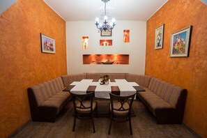 A dining area with a round table, cushioned benches, and framed artwork on the walls.