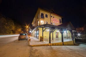 A hotel with a covered outdoor seating area and a sign that reads "HOTEL RESTAURANT KRIST."