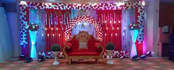 Un escenario decorado en rojo y blanco con un sofá dorado, arreglos florales e iluminación colgante.