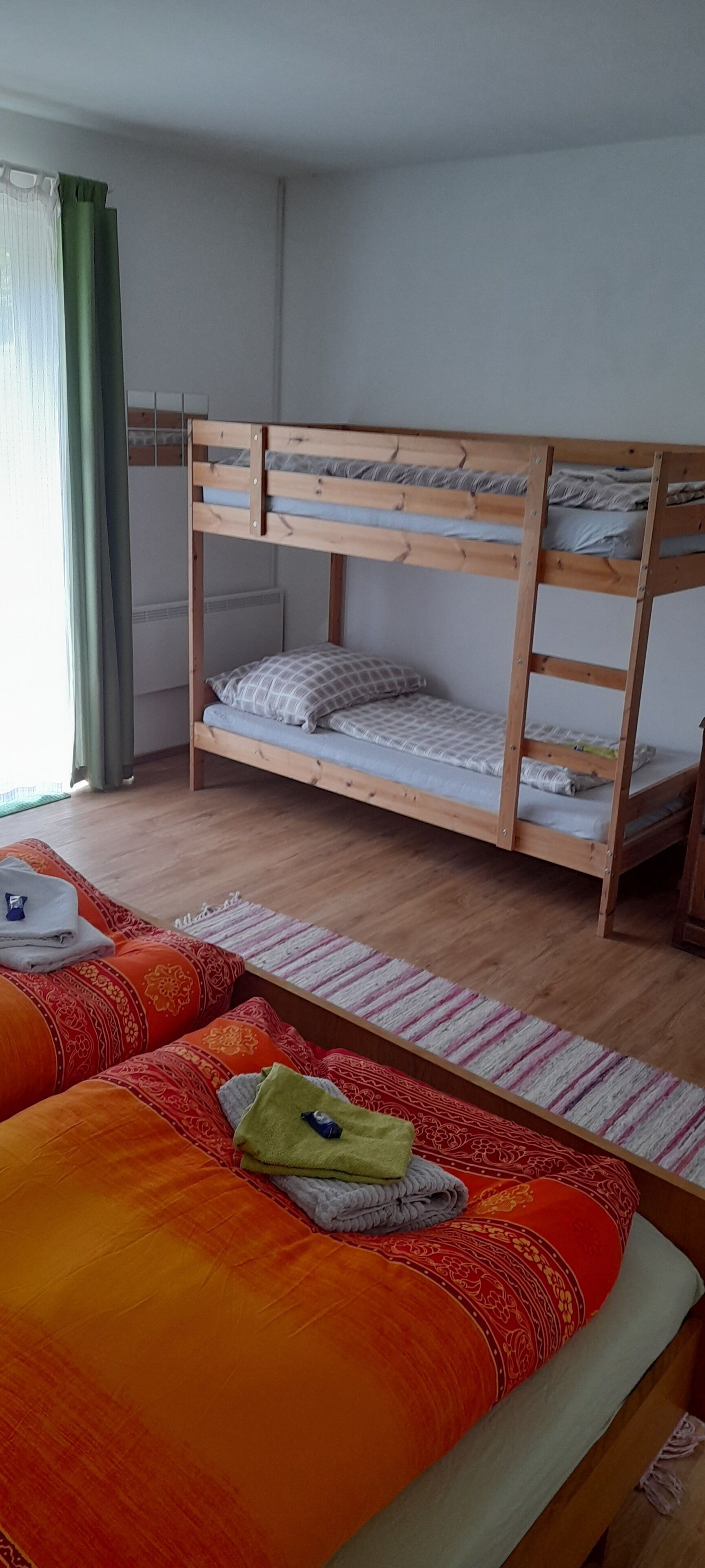 Una habitación con una cama litera, un sofá cama y una ventana con cortinas.
