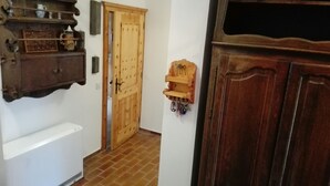A hallway with a wooden door, a radiator, and a shelf with various items. - Cozy and centrally located vacation home 500 meters from the cable car/ski slope (Mitterstoder)