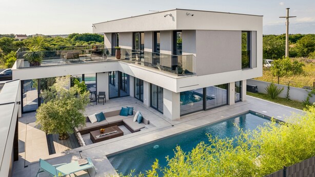 A modern two-story house with a glass balcony, a swimming pool, and outdoor seating. - Villa Marli ZadarVillas (Zaton)