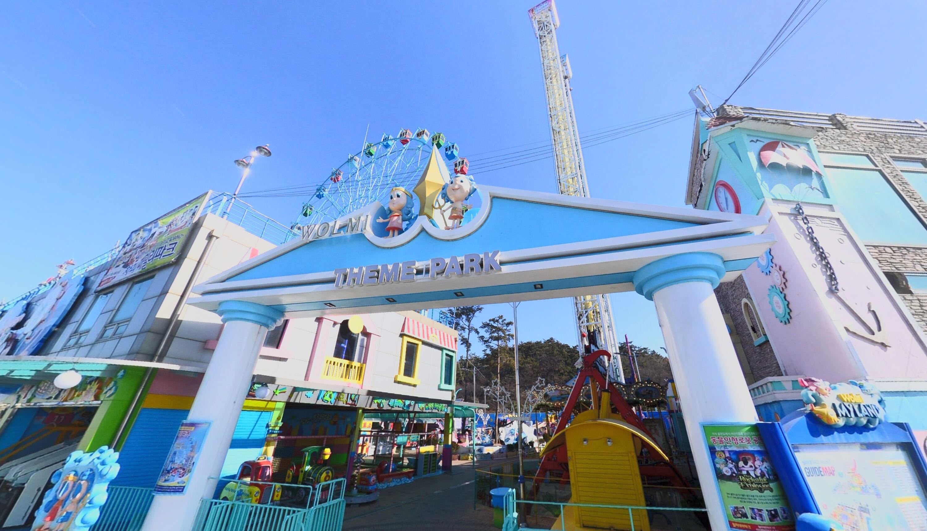A theme park entrance with a Ferris wheel, colorful buildings, and a roller coaster.