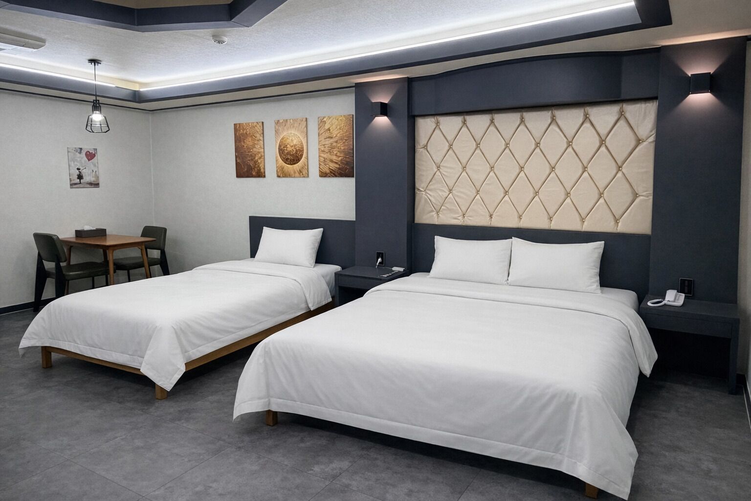 Habitación de hotel con dos camas, un escritorio, sillas y obras de arte en la pared.
