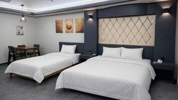 Habitación de hotel con dos camas, un escritorio, sillas y obras de arte en la pared.