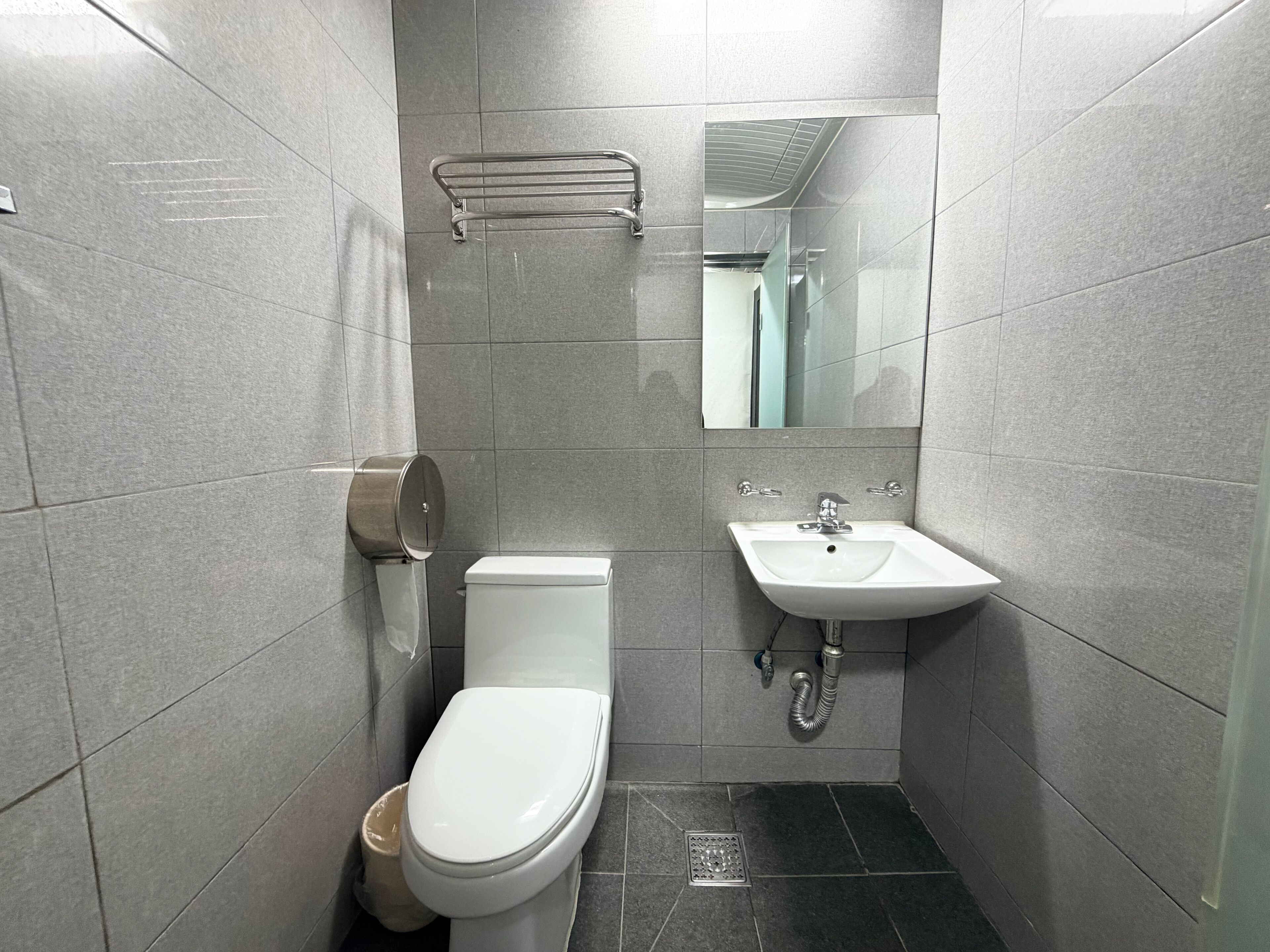 A small, modern bathroom with a toilet, sink, and mirror.