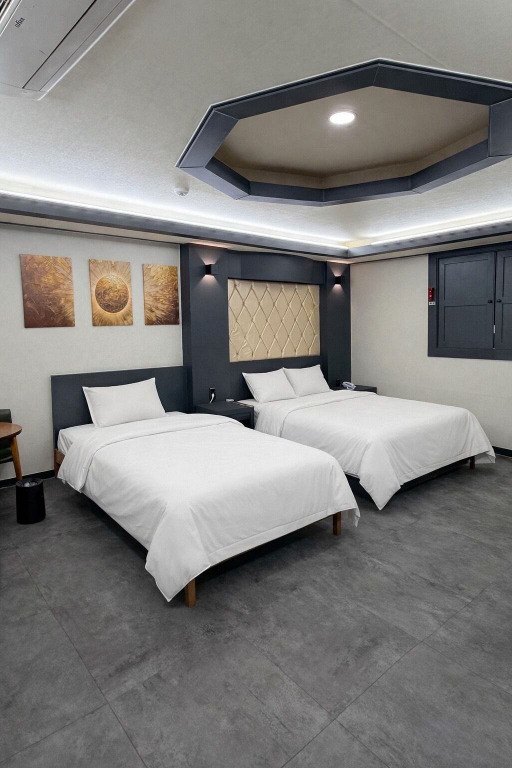 Ein modernes Hotelzimmer mit zwei Betten, einem großen Fenster und einem außergewöhnlichen Deckenstil.