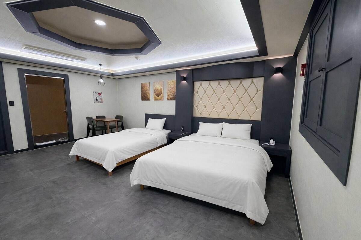 A hotel room with two beds, a desk, and a chair.