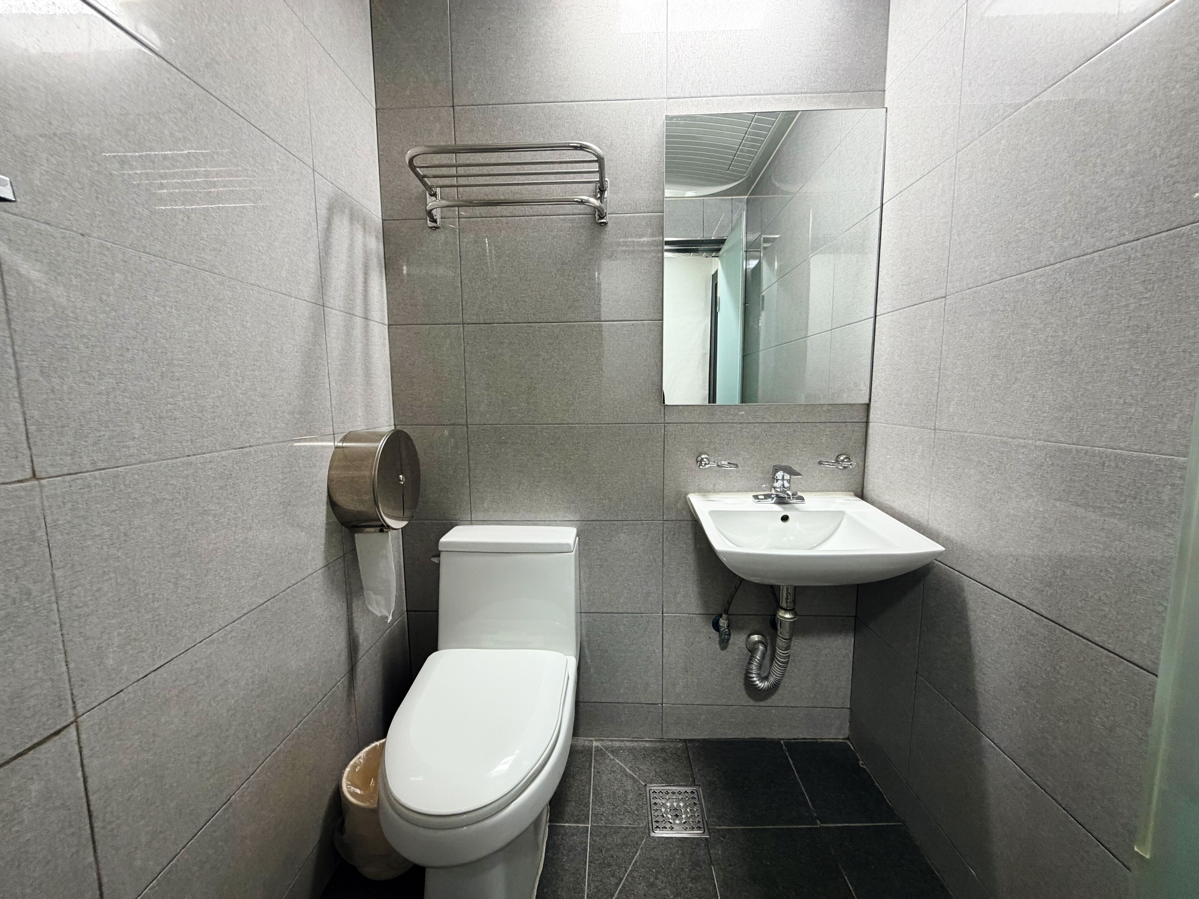 A compact bathroom with a toilet, a sink, and a mirror.