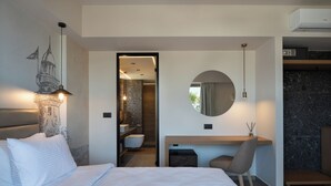 Een moderne hotelkamer met een groot bed, een bureau, een stoel, een ronde spiegel, en een badkamer zichtbaar door een geopende deur.
