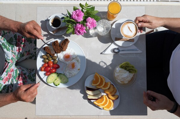 Une table de petit-déjeuner avec des assiettes d’œufs, des toasts et des fruits, ainsi que des tasses de café et de jus de fruits.