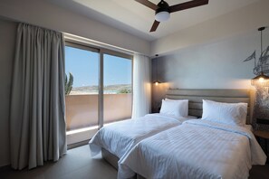 A hotel room with a large bed, a ceiling fan, and a view of the outdoors through a sliding glass door. - Prasonisi Light House Boutique Hotel (Rhodes)