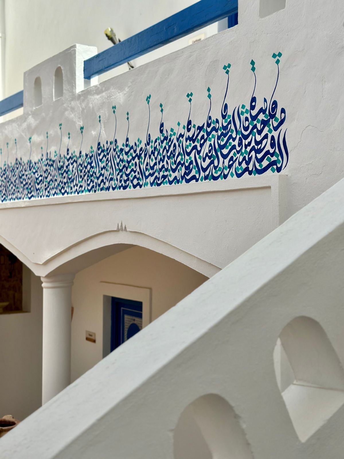 Un edificio blanco con detalles azules y caligrafía árabe.